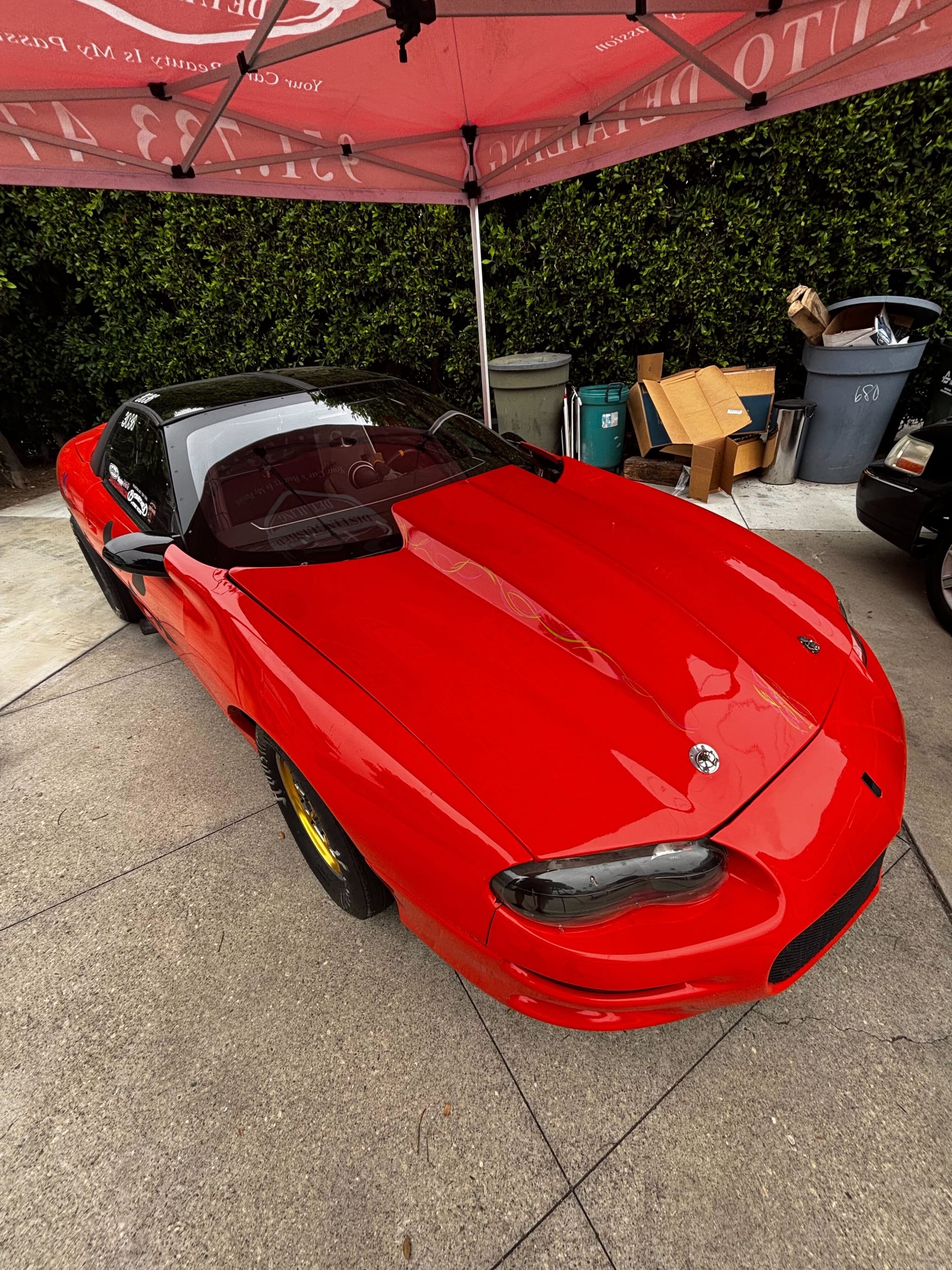 Red Chevrolet Camaro detailed under the Distinguished Detailing mobile canopy
